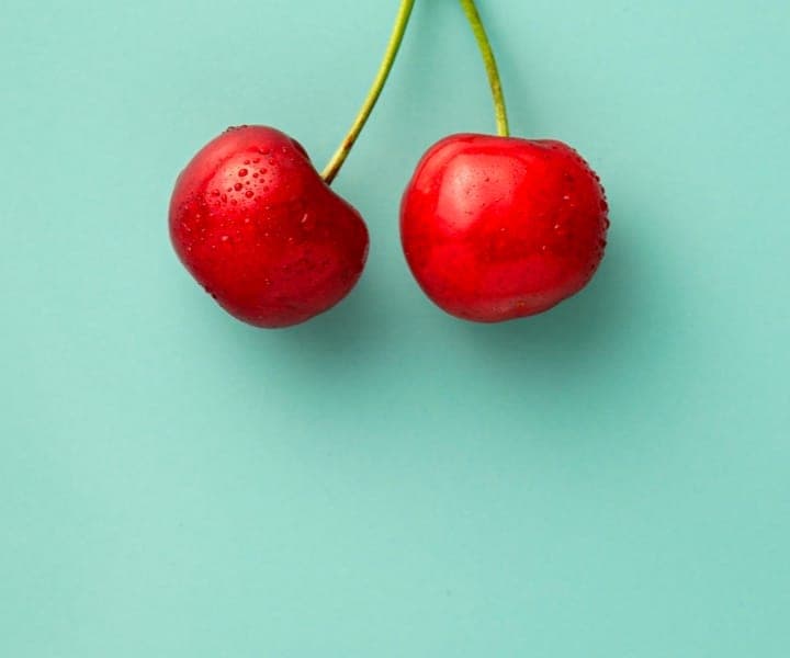 Two cherries on a light blue background